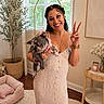Ivy is registered to the contest to win money with this photo: blinds, bracelet, candle, dog, dog_bed, dress, french_bulldog, happy, home_decor, indoor, necklace, peace_sign, plant, potted_plant, rug, side_table, smile, window, woman, wooden_floor