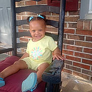 Emarey is registered to the contest to win money with this photo: blue_bows, brick_wall, casual, child, cushion, cute, daylight, footwear, front_portrait, hair, happy, home, outdoor, person, rocking_chair, sitting, smile, sunny, toddler, yellow_clothing