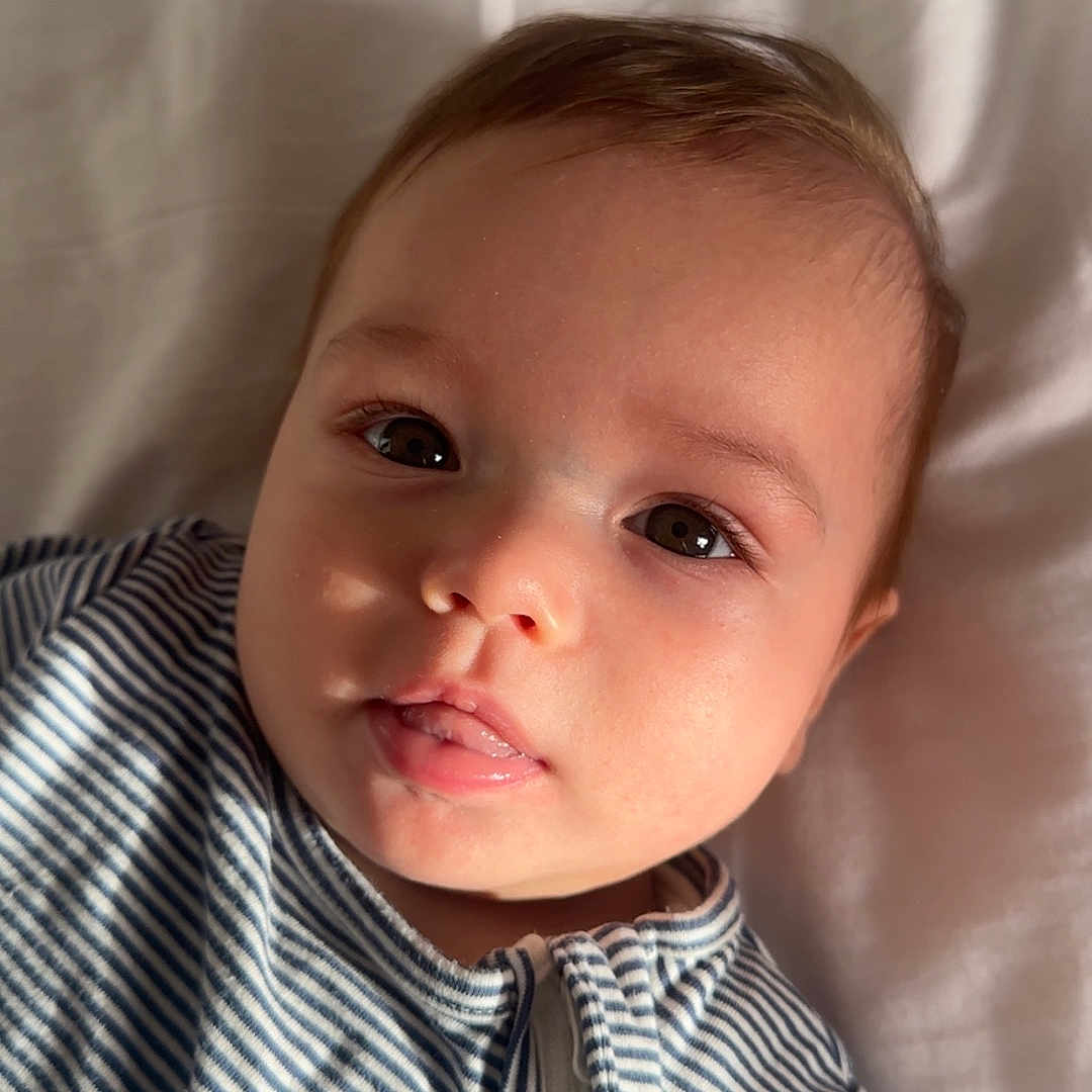 Jaziya joined the competition — help win amazing prizes! baby, blanket, child, closeup, cute, expression, eyes, face, human, indoors, infant, lying_down, mouth, person, portrait, skin, soft_light, striped_clothing, young, zipper