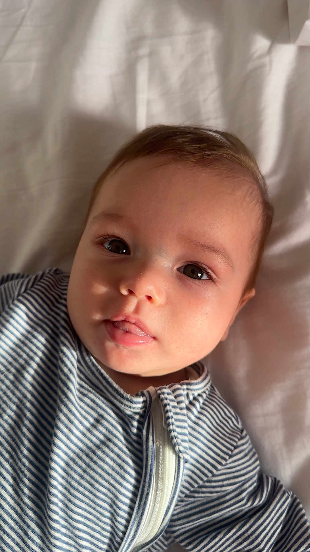 Jaziya joined the competition — help win amazing prizes! baby, child, face, portrait, striped_clothing, infant, cute, lying_down, soft_light, expression, young, human, skin, eyes, mouth, zipper, blanket, indoors, closeup, person