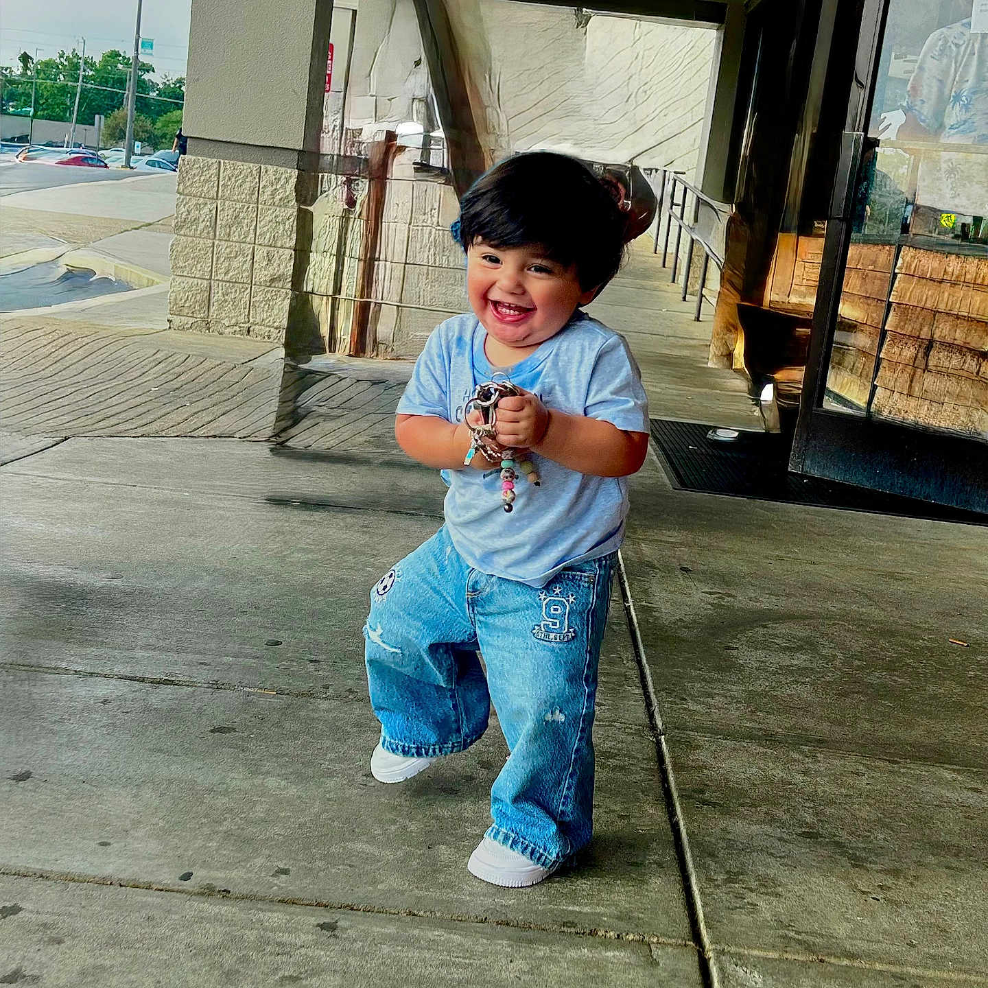 Mteo is registered to the contest to win money with this photo: child, toddler, smiling, happy, jeans, tshirt, concrete, sidewalk, urban, building, door, glass, reflection, keys, playful, person, walking, outdoor, daylight, cute