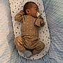baby, sleeping, pacifier, pajamas, bassinet, blanket, stars, moon, soft, cozy, infant, child, cute, resting, blue, brown, patterned, fabric, indoors, peaceful