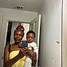 Blessan joined the competition — help win amazing prizes! woman, baby, mirror, selfie, yellow_dress, headscarf, indoor, door, pajamas, baseball_pattern, person, holding, curious, reflection, smartphone, casual, home, portrait, smile, child