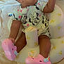 baby, child, infant, seat, pink_shoes, minnie_mouse, clothing, hair_clip, indoor, curious, cute, yellow, pattern, soft, comfort, person, baby_seat, hand, footwear, toy