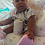 Ava joined the competition — help win amazing prizes! baby, child, infant, seat, baby_seat, toy, shoe, pink_shoe, hand, face, curly_hair, hair_bow, clothing, patterned_clothing, bear_pattern, indoor, blanket, soft_surface, wooden_wall, cute
