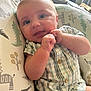 baby, infant, child, plaid_clothing, cushion, animal_print, face, hands, blue_eyes, indoor, cute, portrait, sitting, soft_light, buttoned_shirt, newborn, skin, expression, comfort, young