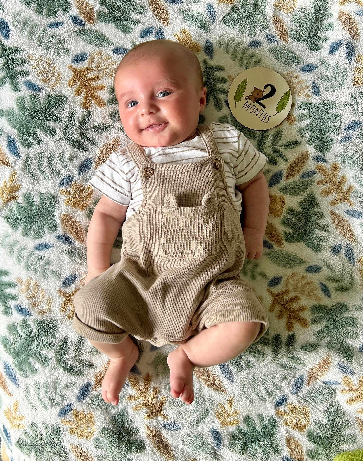 Lowen joined the competition — help win amazing prizes! baby, infant, smiling, face, blanket, pattern, overalls, clothing, milestone_card, text, skin, foot, hand, striped_shirt, cute, lying_down, soft_texture, happy, indoors, young_child