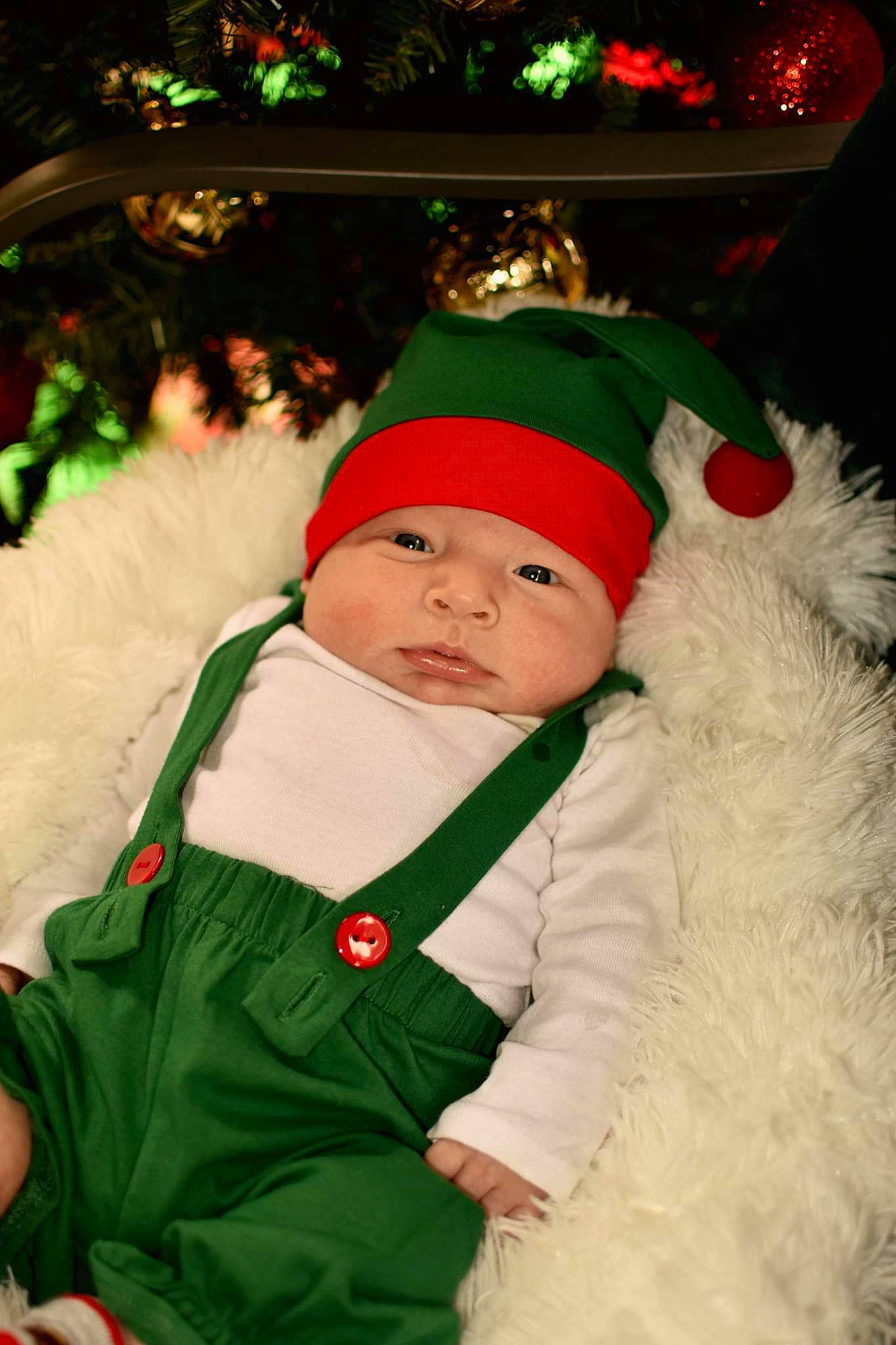 John is registered to the contest to win money with this photo: christmas, christmas_decoration, christmas_ornament, christmas_tree, event, fun, fur_clothing, green, happy, hat, head, headwear, holiday, human_body, lap, lighting, person, santa_claus, sleeve, standing