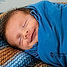 baby, newborn, smiling, sleeping, blue_blanket, knitted_blanket, cozy, portrait, face, infant, peaceful, resting, cute, child, wrapped, soft, closeup, young, indoors, warm