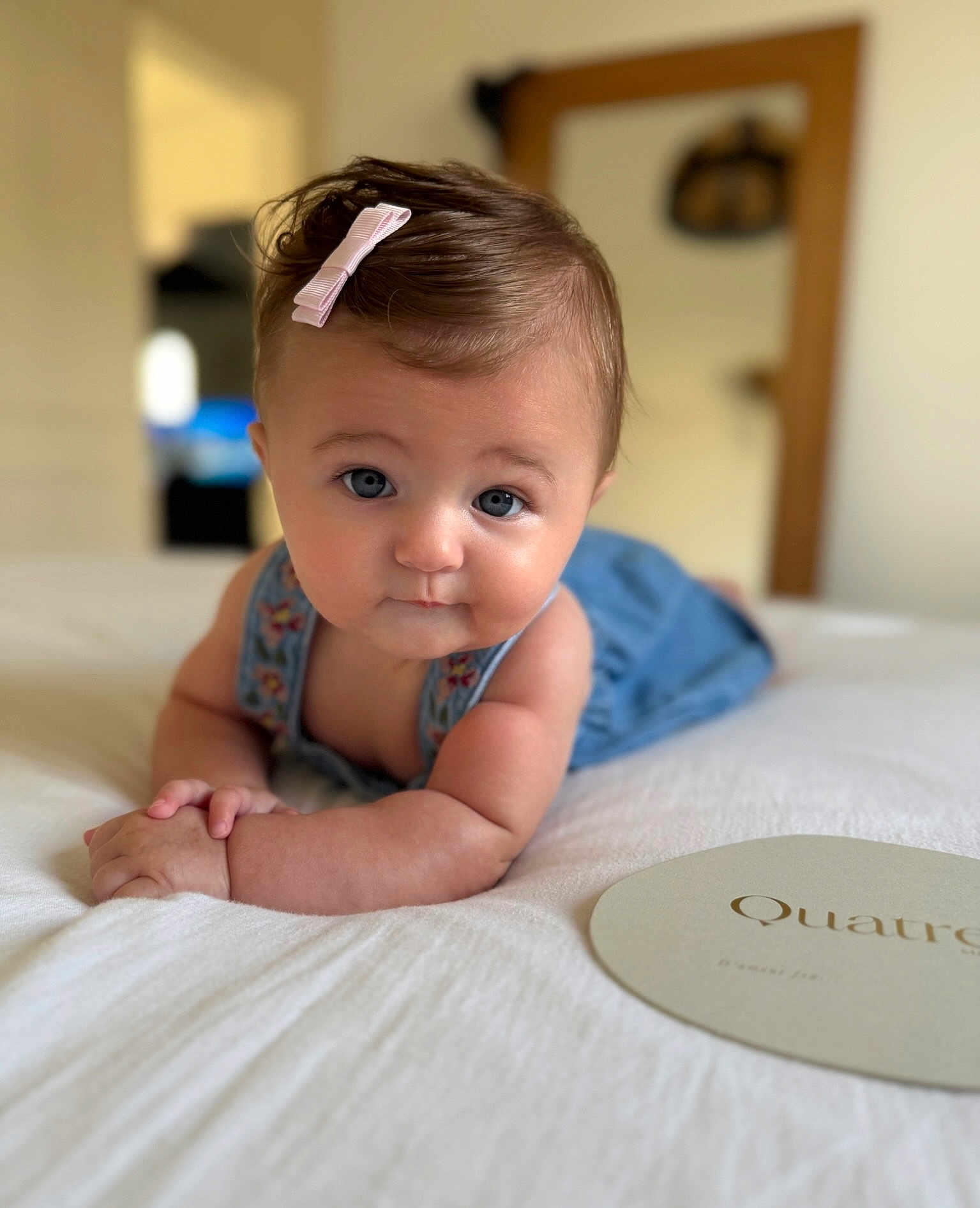 Valentine a rejoint le concours — aidez-le/la à gagner de superbes lots ! baby, pink_bow, blue_eyes, baby_clothing, bed, white_bedspread, indoor, portrait, child, cute, infant, hands, face, skin, hair, room, blurred_background, curious_expression, lying_down, soft_lighting