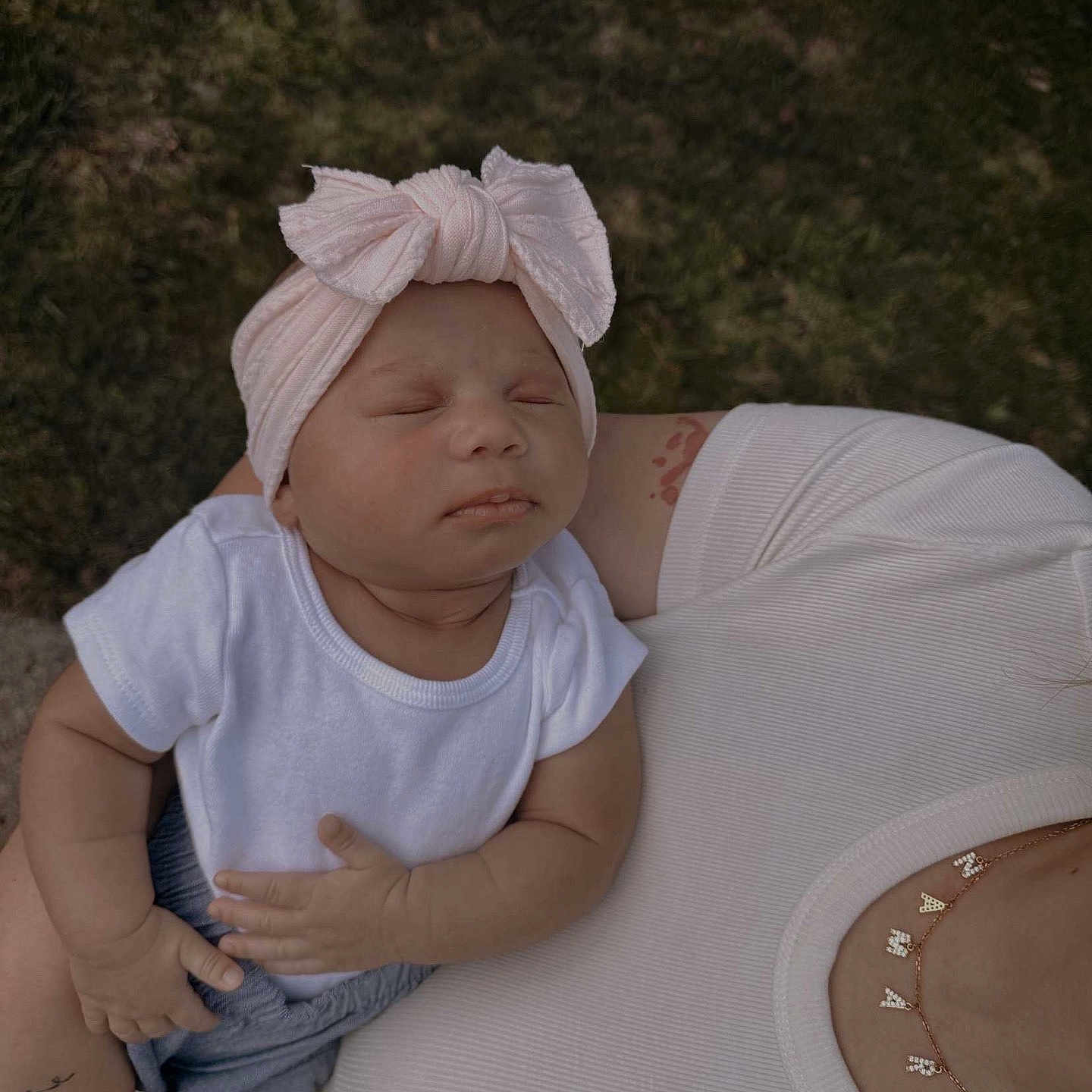 Namari is registered to the contest to win money with this photo: adult, arm, baby, child, closeup, cute, grass, headband, holding, infant, necklace, outdoor, peaceful, person, pink, portrait, skin, sleeping, tattoo, white_clothing
