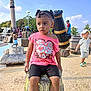 child, toddler, outdoor, playground, water_park, barrel, pink_shirt, shorts, people, sunny, daytime, trees, blue_sky, play, hat, footwear, expression, park, fun, summer