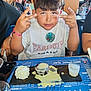 boy, casual_clothing, child, dessert, dining, food, glass, hand_gesture, indoor, milk, paraguay, people, plate, restaurant, short_hair, smile, spilled_sauce, table, whipped_cream, white_tshirt