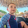 Malo a rejoint le concours — aidez-le/la à gagner de superbes lots ! child, toddler, swimsuit, blue, striped_clothing, beach, umbrella, thatched_roof, outdoor, sunny, person, relaxed, woman, nature, palm_tree, vacation, summer, portrait, seating, casual