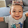 toddler, child, smiling, face, indoor, couch, pillow, window, tshirt, animal_print, leopard, happy, portrait, young_child, home, casual_clothing, cute, brown_eyes, short_hair, cozy