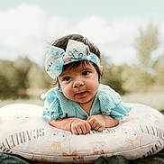 Scarlett joined the competition — help win amazing prizes! baby, child, clothing, cute, daylight, expression, face, grass, hands, head, headband, infant, lying_down, nature, outdoor, pillow, portrait, smile, soft_fabric, young_child