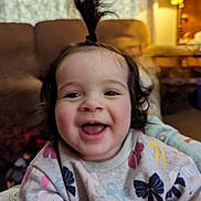 Scarlett joined the competition — help win amazing prizes! toddler, child, smiling, happy, indoor, portrait, baby, hair_tie, sweater, patterned_clothing, lamp, couch, living_room, cute, face, person, young_child, playful, joyful, fun