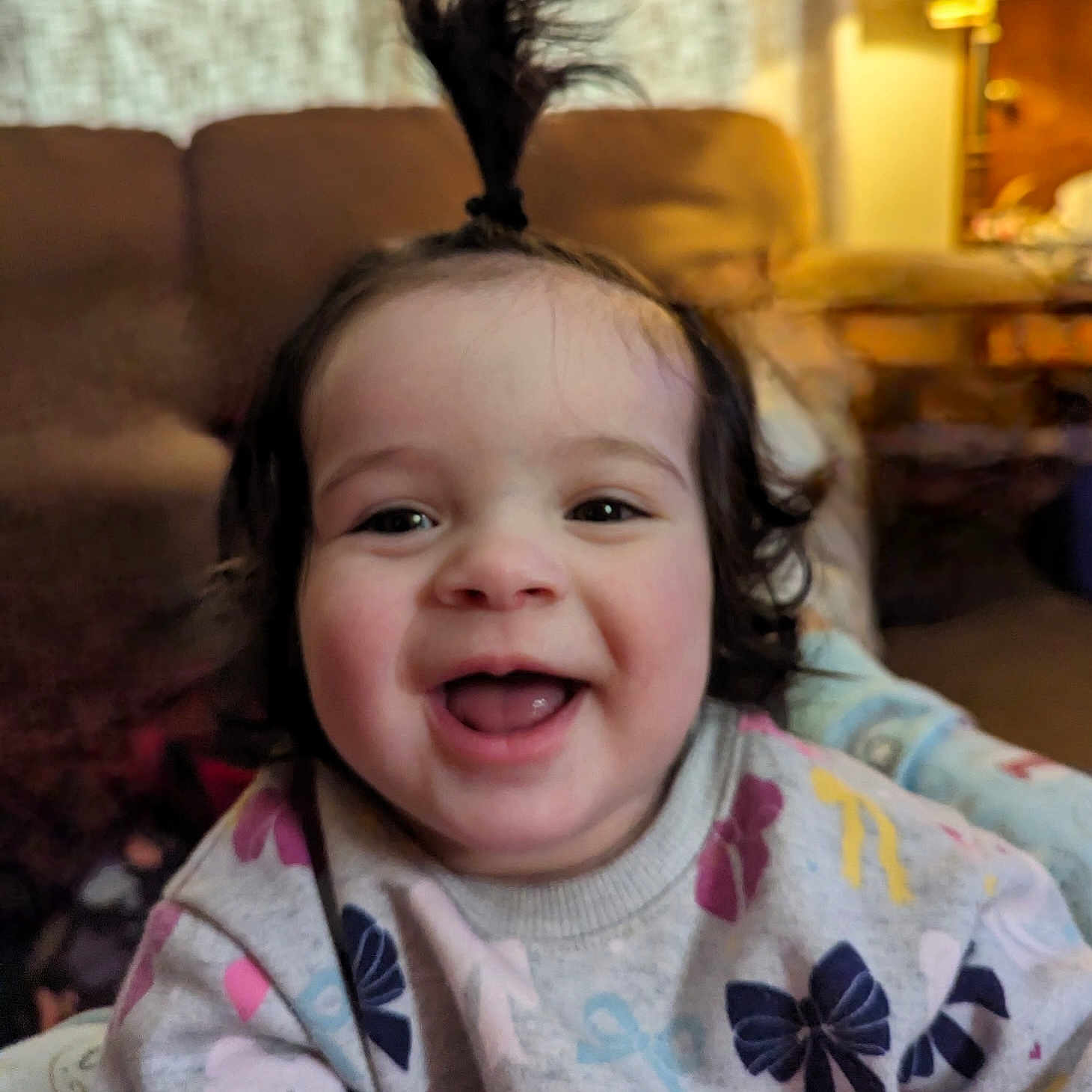 Scarlett joined the competition — help win amazing prizes! toddler, child, smiling, happy, indoor, portrait, baby, hair_tie, sweater, patterned_clothing, lamp, couch, living_room, cute, face, person, young_child, playful, joyful, fun
