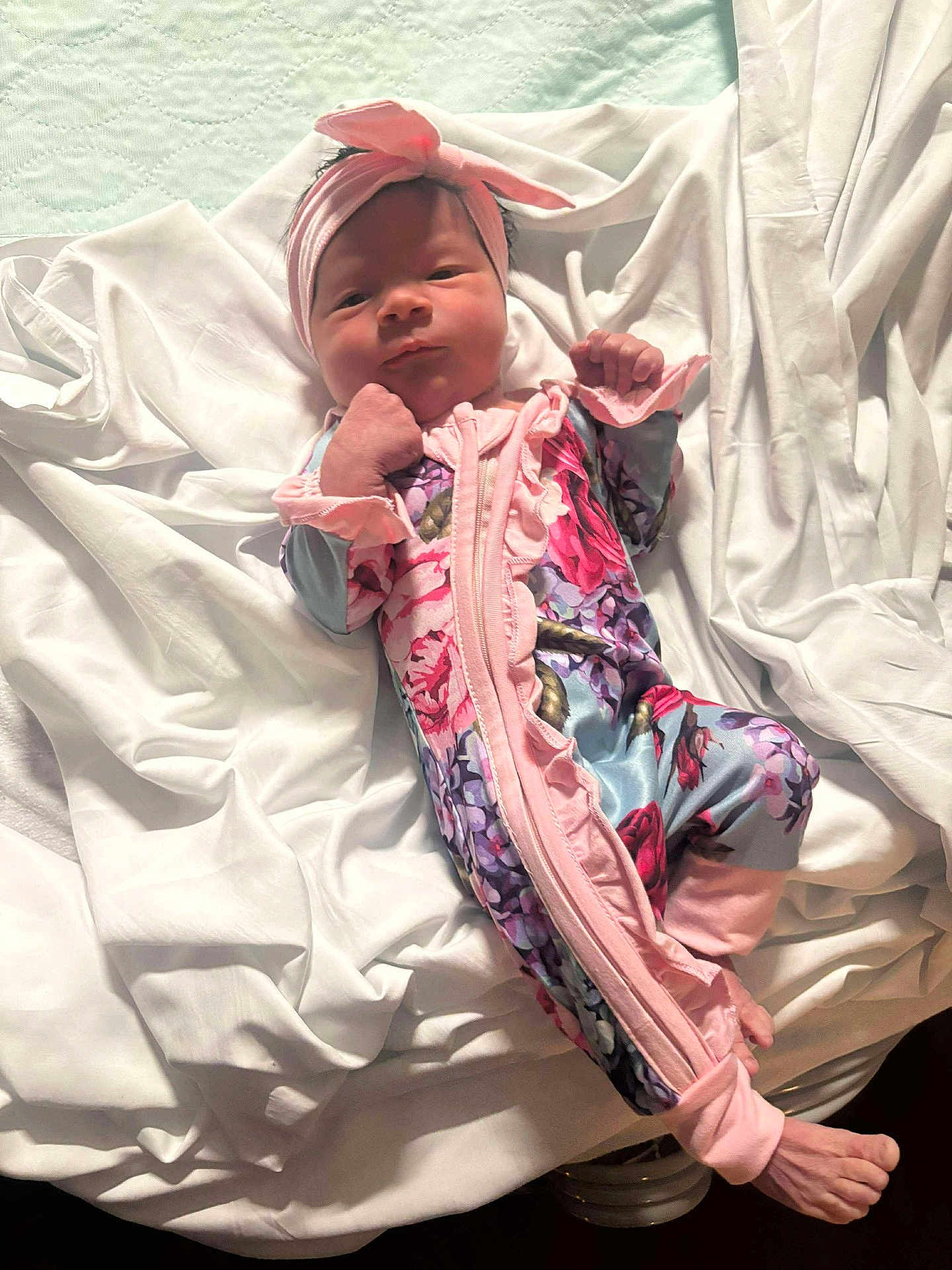 Scarlett is registered to the contest to win money with this photo: baby, newborn, infant, blanket, headband, onesie, pink, floral, clothing, sleepwear, soft, bed, cute, face, hands, feet, lying_down, portrait, indoor, child