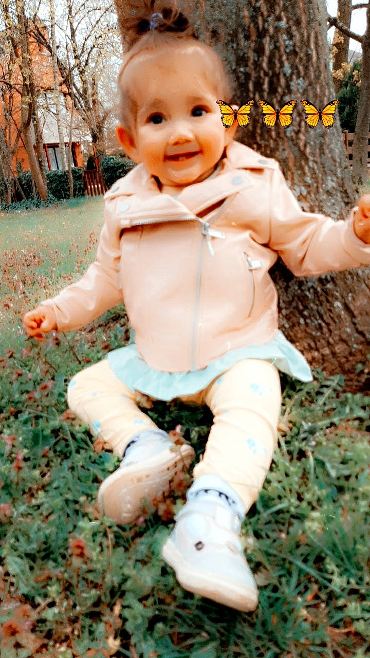 Fleur a rejoint le concours — aidez-le/la à gagner de superbes lots ! child, doll, fictional_character, fun, fur, gesture, grass, hand, happy, joy, leg, pattern, people_in_nature, person, plant, sitting, smile, soil, toy, tree