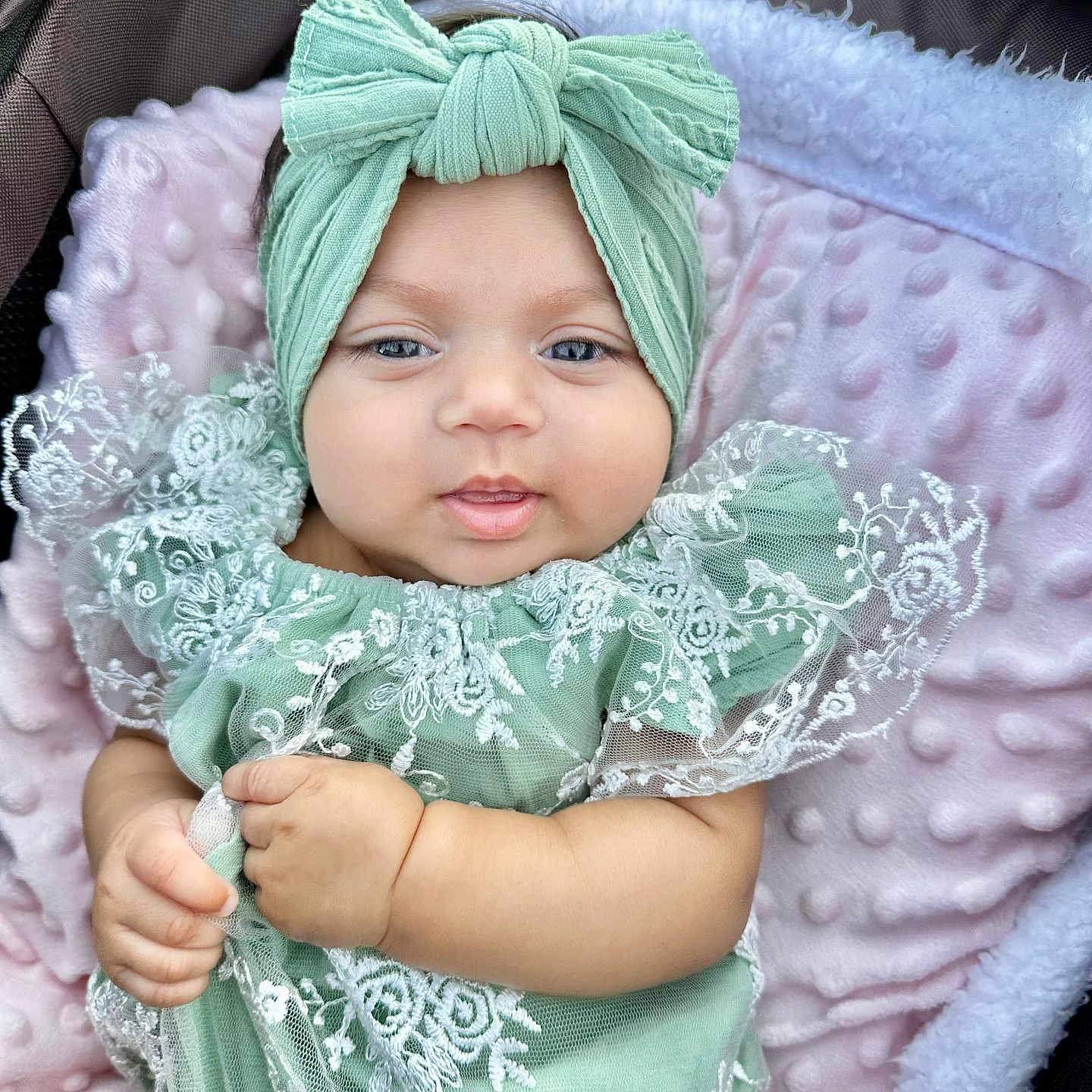 Alisha joined the competition — help win amazing prizes! adorable, baby, blanket, bow, child, closeup, cute, eyes, face, green_clothing, hand, headband, indoors, infant, lace, pink_blanket, portrait, sitting, smile, soft_texture