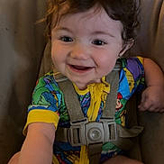 Oceann joined the competition — help win amazing prizes! toddler, baby, child, curly_hair, smiling, colorful_clothing, onesie, baby_seat, harness, happy, indoor, wood_floor, person, cute, infant, young_child, portrait, seat_belt, reaching, playful