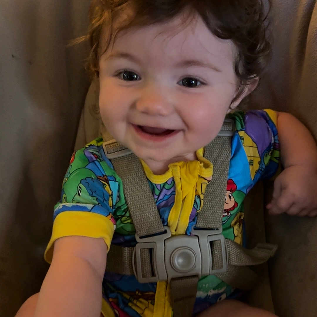 Oceann joined the competition — help win amazing prizes! toddler, baby, child, curly_hair, smiling, colorful_clothing, onesie, baby_seat, harness, happy, indoor, wood_floor, person, cute, infant, young_child, portrait, seat_belt, reaching, playful