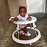 Aylani is registered to the contest to win money with this photo: toddler, baby_walker, pink_bows, snack, colorful_sneakers, wooden_floor, porch, door, brick_wall, curious, child, indoors, playful, candid, clothing, footwear, person, young_child, cute, exploring