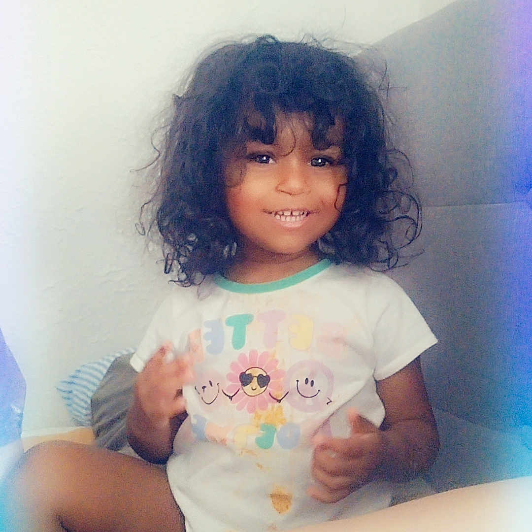 Haislynn joined the competition — help win amazing prizes! bodypart, child, clothing, couch, cushion, face, female, finger, furniture, girl, hand, happy, head, person, photography, portrait, shorts, sitting, smile, t_shirt