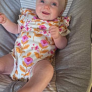 Darcie-Rae is registered to the contest to win money with this photo: baby, infant, smiling, onesie, floral_pattern, blue_eyes, cushion, baby_seat, comfortable, happy, child, cute, indoor, portrait, skin, head, arms, legs, furniture, baby_clothing