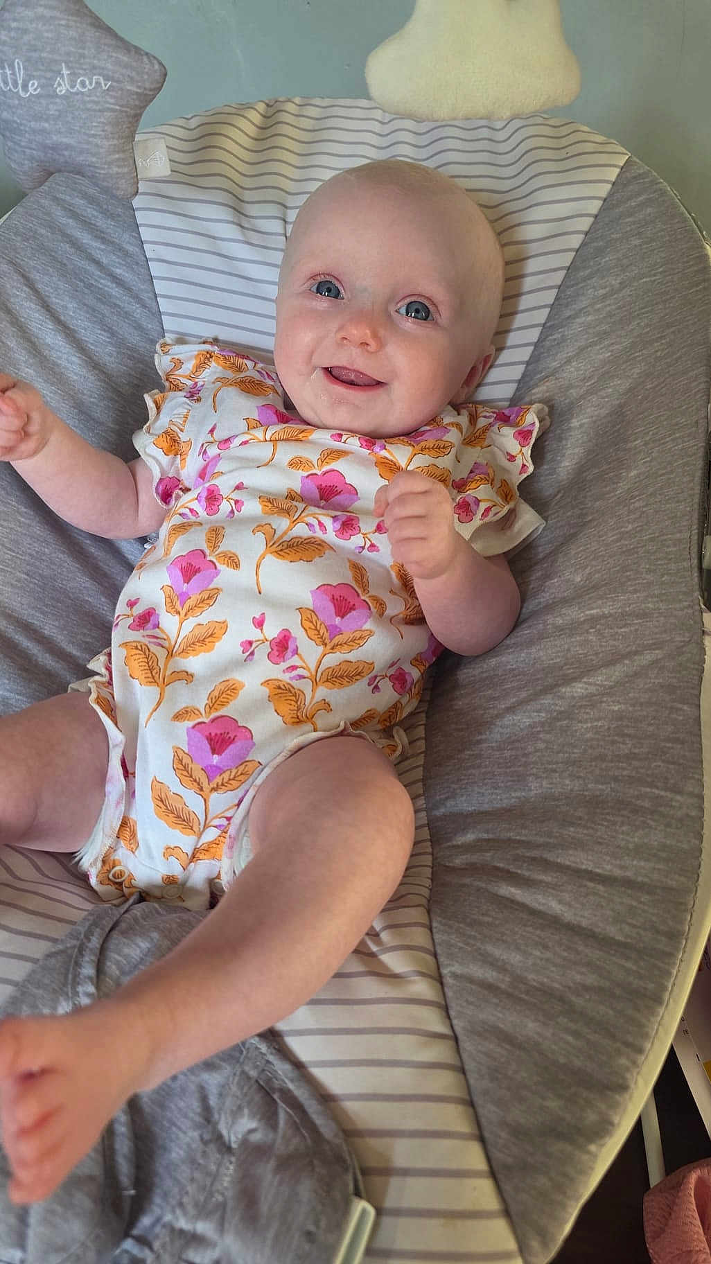Darcie-Rae is registered to the contest to win money with this photo: baby, infant, smiling, onesie, floral_pattern, blue_eyes, cushion, baby_seat, comfortable, happy, child, cute, indoor, portrait, skin, head, arms, legs, furniture, baby_clothing
