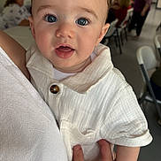 Kingston is registered to the contest to win money with this photo: baby, blue_eyes, blurred_background, buttoned_shirt, casual, child, closeup, curly_hair, cute, expression, family, hand, holding, indoor, infant, people, person, portrait, seated, white_clothing