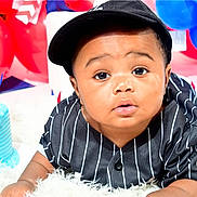 Angelo is registered to the contest to win money with this photo: baby, child, birthday, cake, balloons, blue, red, hat, pinstripe, black_clothing, celebration, party, cute, portrait, face, smiling, happy, infant, indoor, colorful