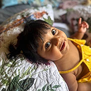 Skyrah joined the competition — help win amazing prizes! baby, child, portrait, face, yellow_clothing, quilt, floral, bed, smile, happy, cute, indoors, skin, hair, person, infant, young_child, expression, lying_down, hand