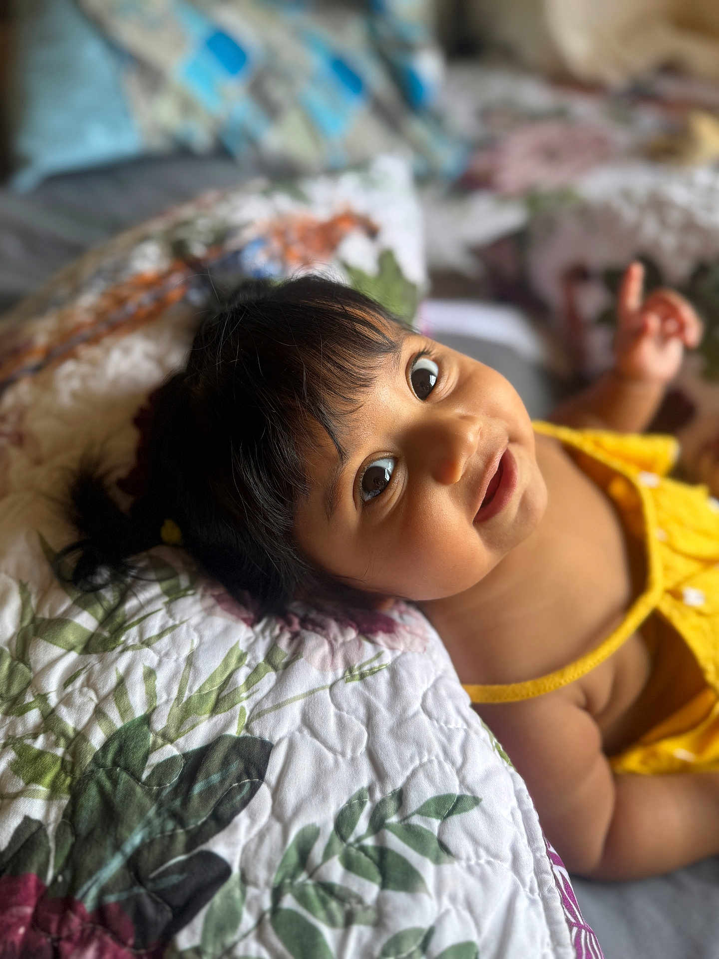 Skyrah joined the competition — help win amazing prizes! baby, child, portrait, face, yellow_clothing, quilt, floral, bed, smile, happy, cute, indoors, skin, hair, person, infant, young_child, expression, lying_down, hand