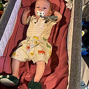 Kendan is registered to the contest to win money with this photo: baby, infant, pacifier, bassinet, blanket, slippers, dinosaur_slippers, clothing, toddler, sleeping_area, soft_toy, indoor, child, cute, lying_down, comfortable, home, fabric, toy, person