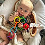 baby, infant, toy, colorful, rings, chewing, blanket, cushion, seat, carpet, clothing, hand, foot, indoor, cute, child, face, expression, comfort, playtime