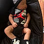baby, sleeping, infant, black_clothing, hat, sneakers, baby_seat, cushion, wood_floor, peaceful, cute, child, newborn, resting, indoors, footwear, person, closeup, casual, relaxing