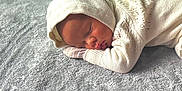 Prince is registered to the contest to win money with this photo: baby, newborn, sleeping, blanket, knitwear, hood, infant, soft, cozy, resting, face, portrait, peaceful, indoor, floor, wooden_floor, closeup, cute, child, warm