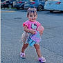 toddler, child, girl, toy, doll, pink, sandals, hair_clips, smiling, parking_lot, sidewalk, purse, shorts, outdoor, cute, happy, walking, clothing, person, daytime