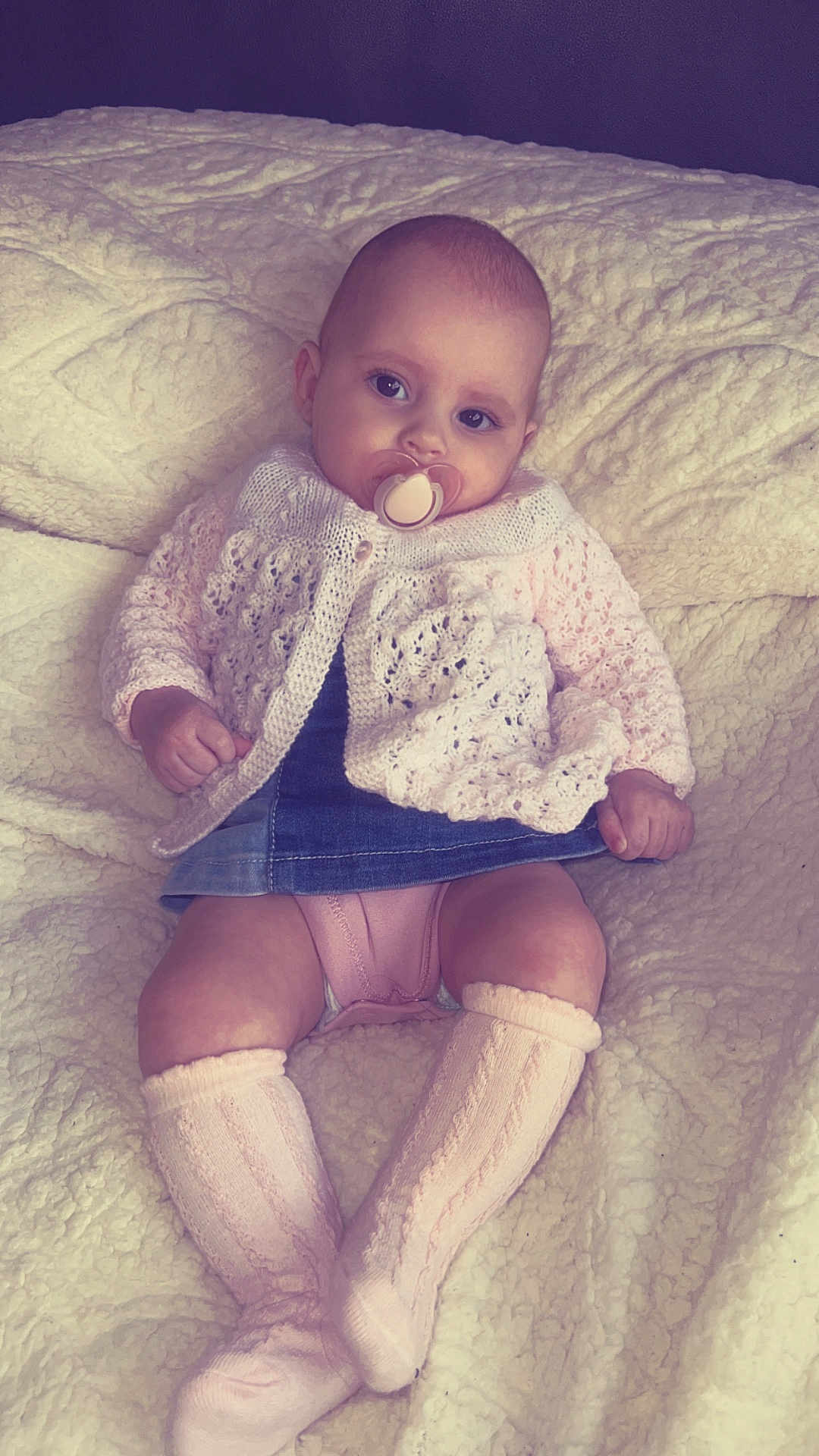 Jasmine is registered to the contest to win money with this photo: baby, infant, pacifier, knit_sweater, denim_skirt, knee_high_socks, blanket, soft_texture, cute, child, portrait, indoors, cozy, comfort, sitting, clothing, face, head, legs, hands
