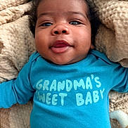 Gabriel joined the competition — help win amazing prizes! baby, infant, blue_clothing, onesie, text_on_clothing, smiling, face, curly_hair, blanket, soft_toy, close_up, cute, happy, child, portrait, indoor, cozy, baby_girl, baby_boy, skin