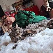 Teo participe au concours pour gagner de l'argent avec cette photo : backpack, blanket, blurred_background, casual_clothing, cat, cozy, curly_hair, curtain, fluffy_cat, furniture, green_hoodie, home, indoor, person, radiator, relaxed, shelf, smiling, soft_texture, television