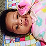baby, blanket, carpet, child, colorful, cozy, cute, face, floral_pattern, head, indoors, infant, lying_down, pajamas, person, portrait, quilt, sleepy, soft_texture, young_child