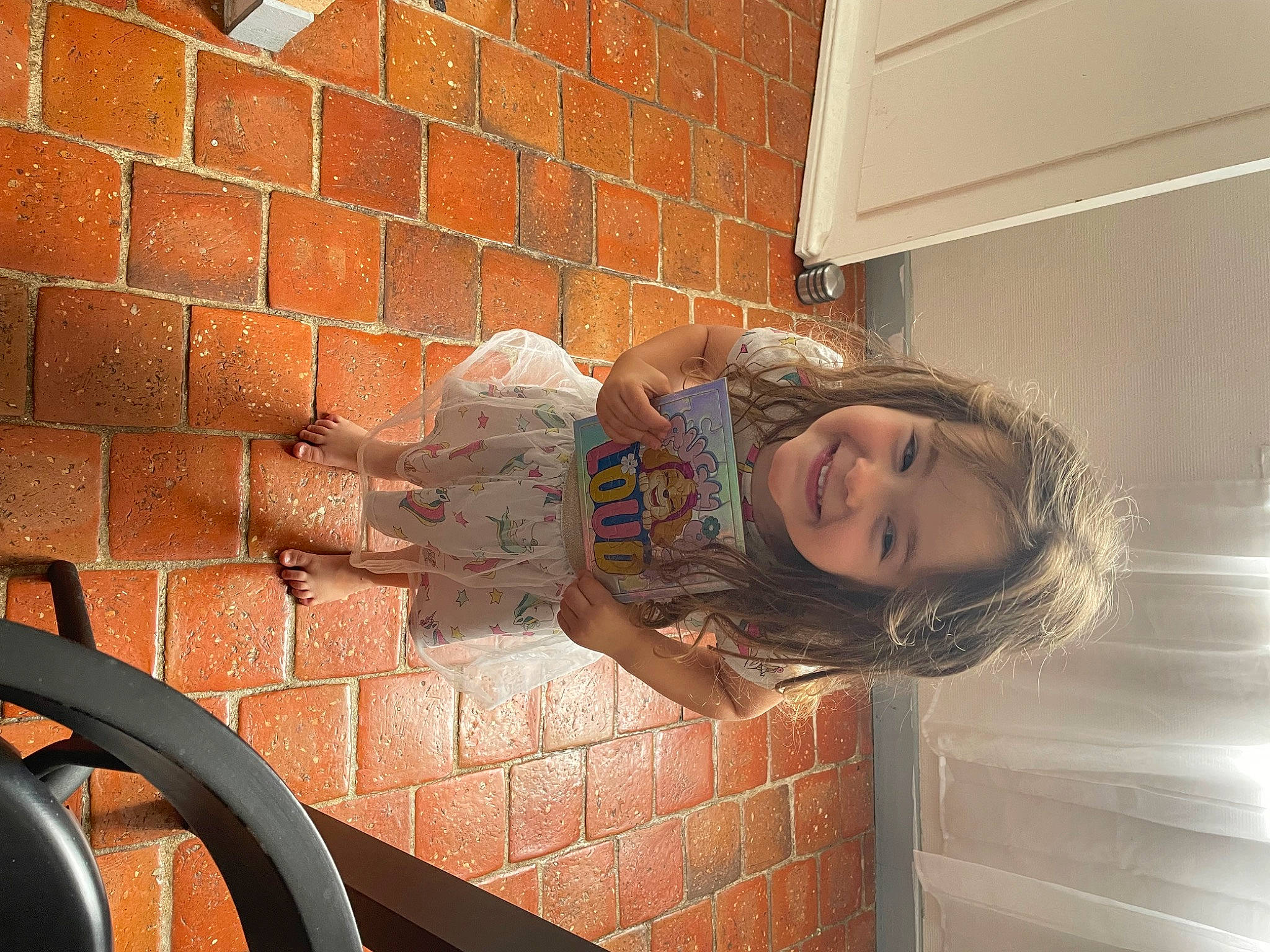 Maëlle a rejoint le concours — aidez-le/la à gagner de superbes lots ! automotive_exterior, brick, brickwork, child, flooring, fun, happy, human_leg, joy, pattern, person, room, sitting, smile, steering_wheel, tints_and_shades, toddler, vehicle_door, wall, window