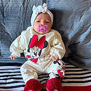 Jacqueline joined the competition — help win amazing prizes! apparel, baby, blanket, child, clothing, cute, face, headband, indoors, infant, mickey_mouse, minnie_mouse, pacifier, person, pillow, red_slippers, resting, sitting, soft, striped