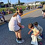 child, children, parade, street, candy, bag, crowd, daylight, outdoor, people, grass, car, house, road, sidewalk, clothing, shoes, glasses, fun, event