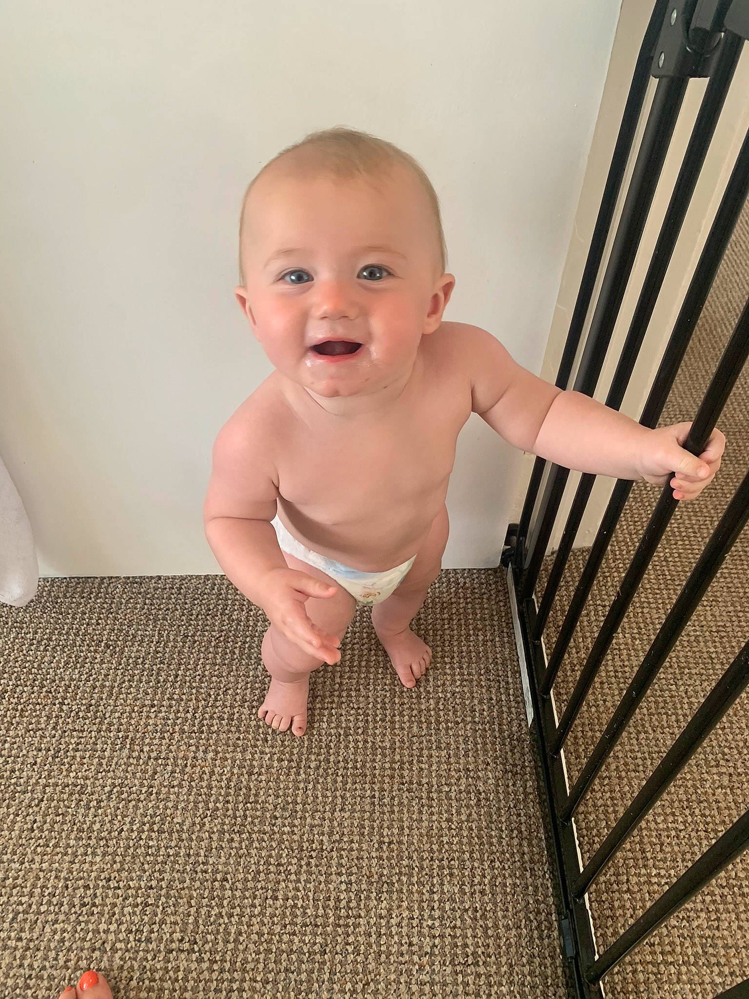 Olivia is registered to the contest to win money with this photo: baby, baby_toddler_clothing, cheek, chest, comfort, eye, finger, floor, flooring, foot, happy, human_leg, iris, person, sitting, skin, smile, standing, thumb, toddler