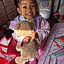 bedroom, child, clothing, drawer, floor, girl, hair_buns, happy, indoor, jacket, laundry_basket, person, pink, plush_toy, shoes, smiling, storage, sunlight, teddy_bear, toy
