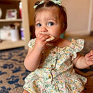 Isla is registered to the contest to win money with this photo: baby, biting, bodypart, clothing, couch, dress, eating, face, finger, food, furniture, hand, hardwood, head, person, photography, portrait, sitting, sweets, wood